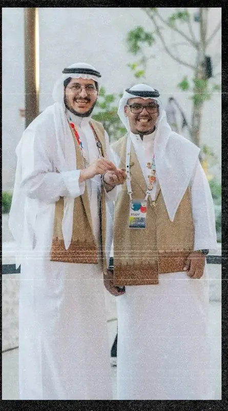 Two Saudi Pavilion staff members in the front-of-house uniforms, outdoors at Expo 2025 Osaka